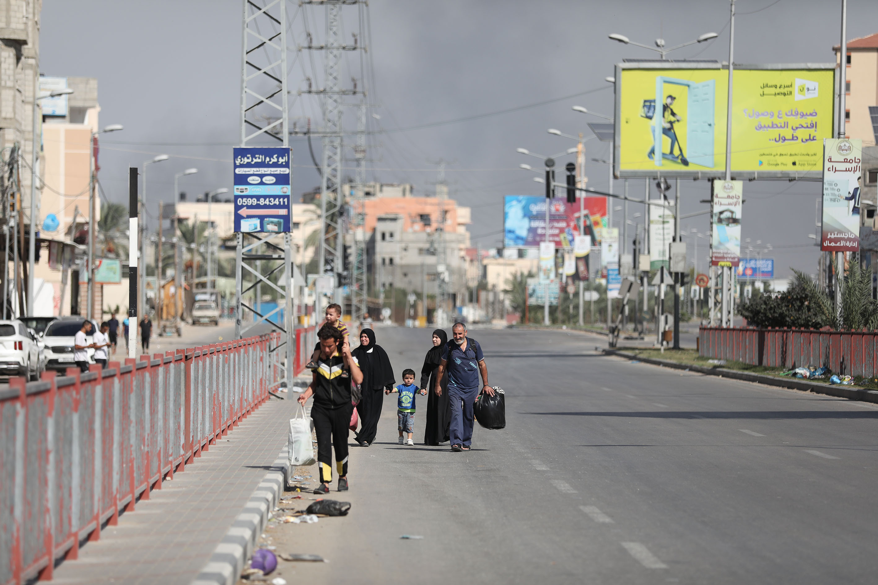 2023年10月30日、イスラエルによるガザ市への攻撃後、立ち上る煙と、わずかな荷物を持って街を去るパレスチナ人の姿 (Getty Images)