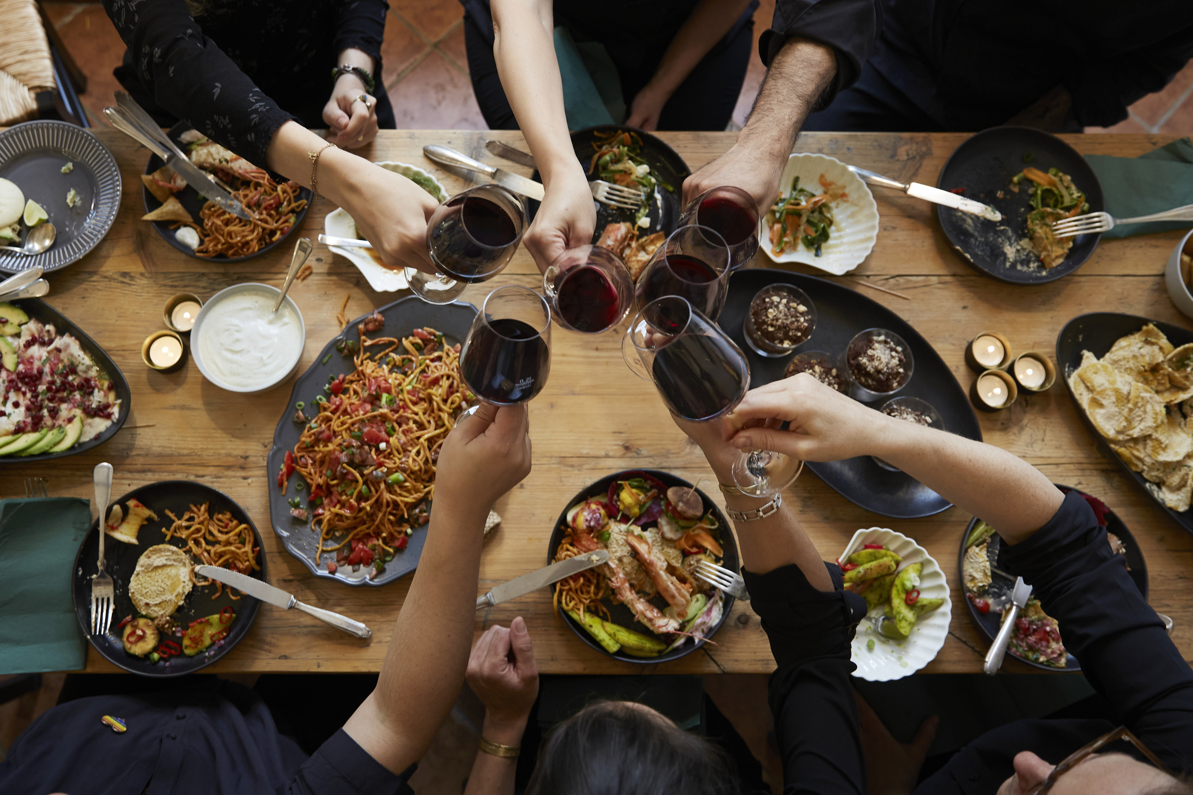 A dinner table seen from above with people toasting their glasses