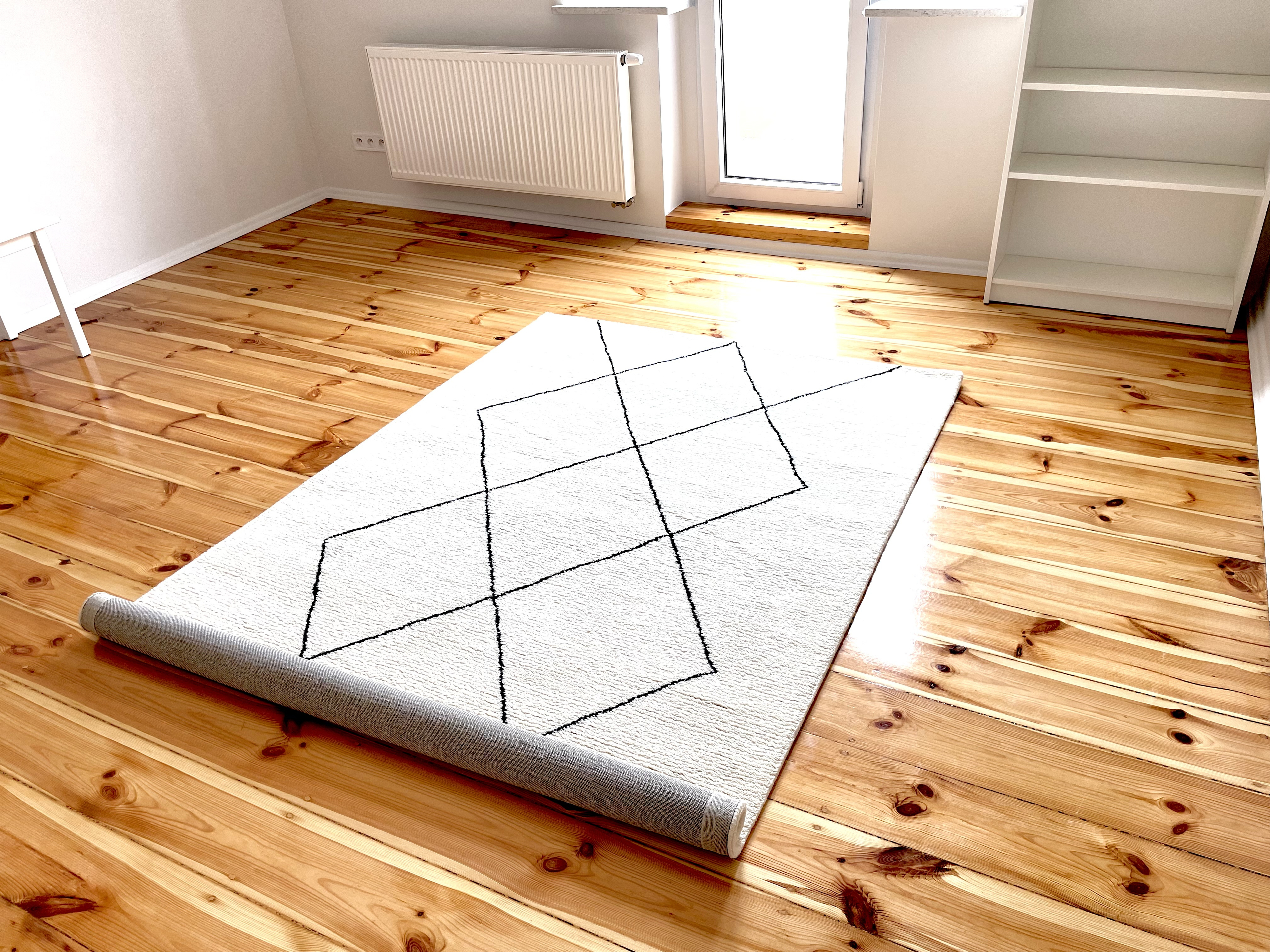 A minimal rug being laid out in a room