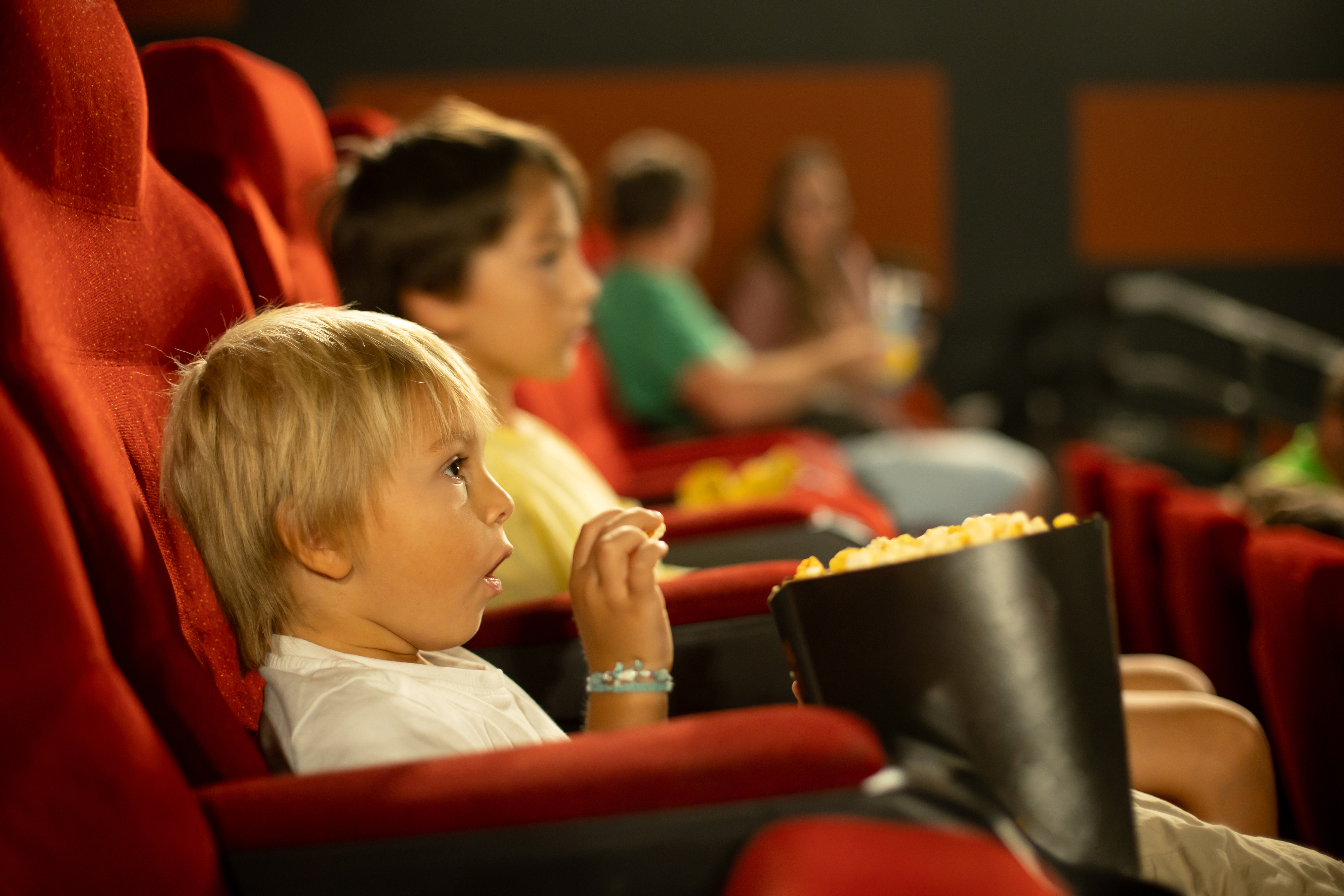 A child eating popcorn in a movie theater