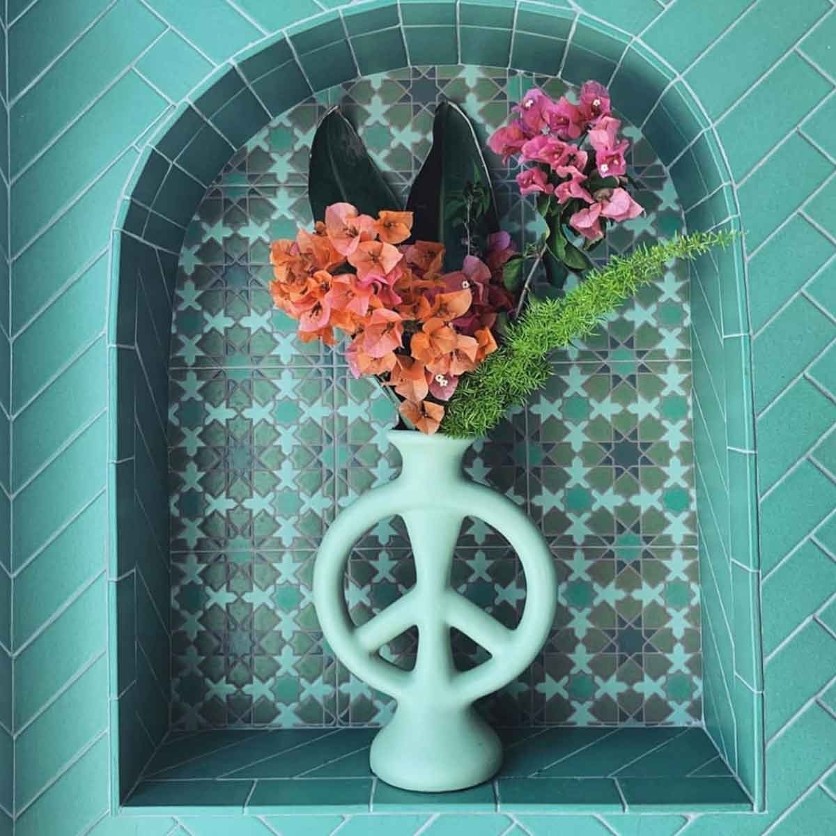 teal vase with a peace-sign design in the middle
