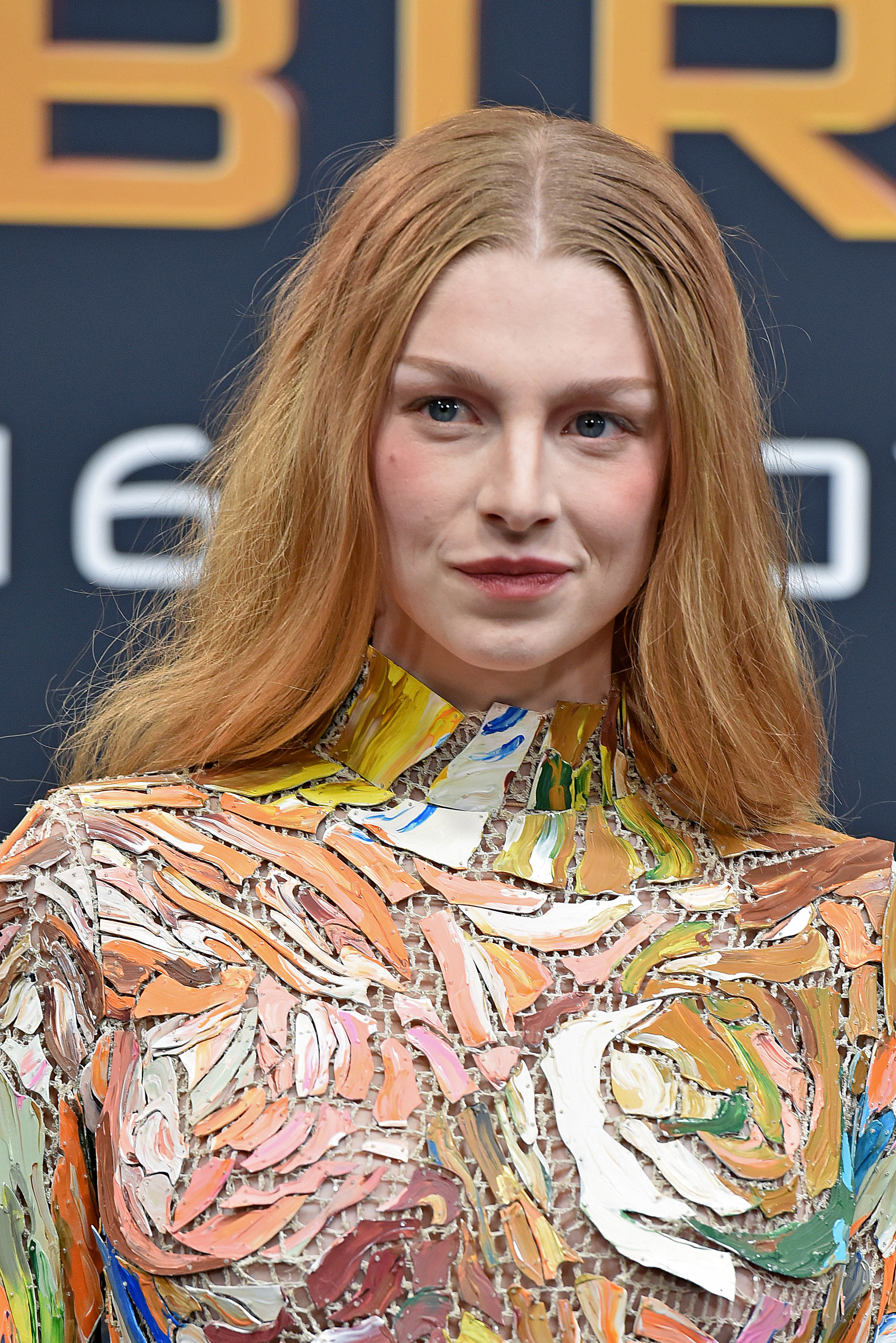 Close-up of Hunter in a multicolored long-sleeved, high-neck dress at a media event
