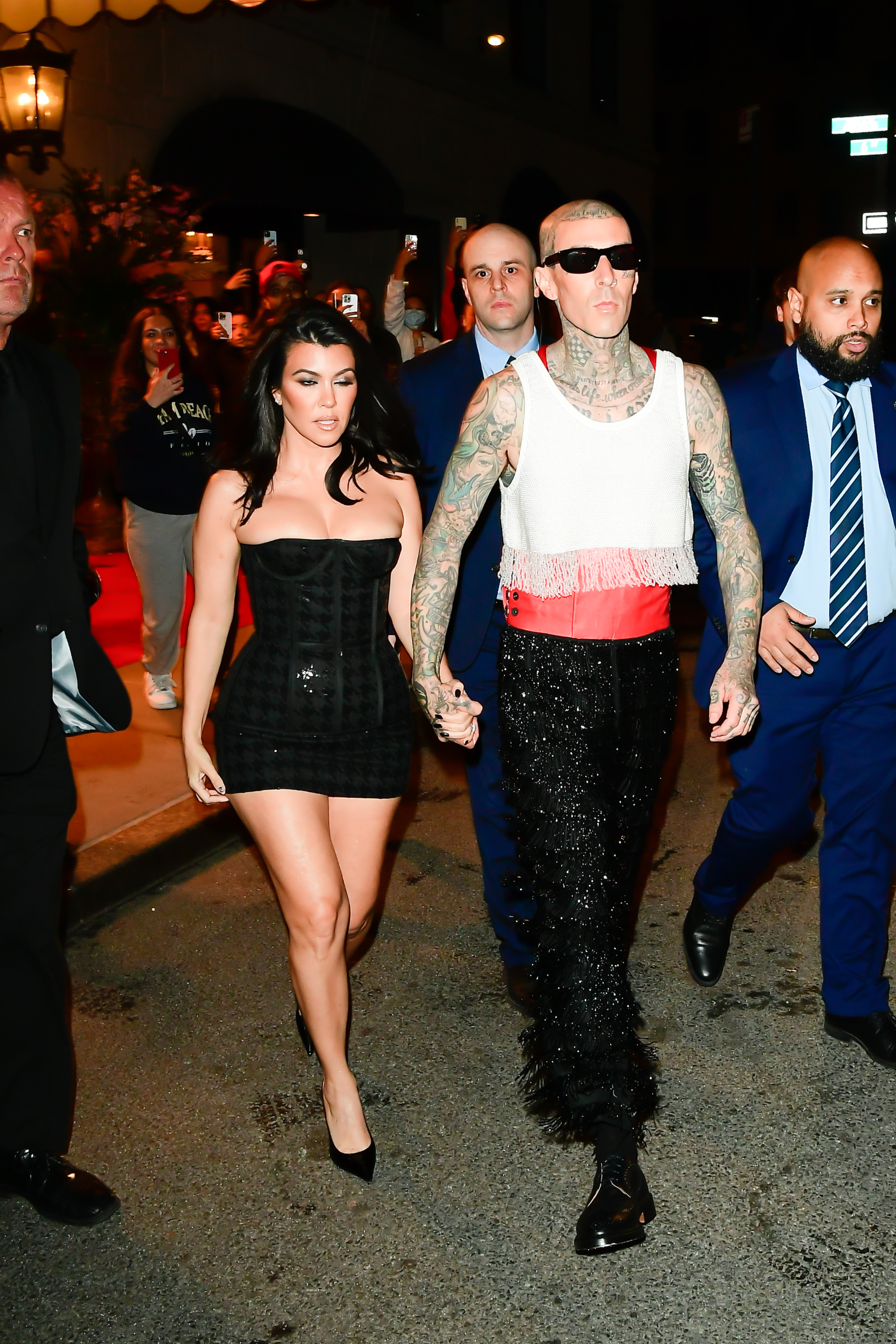 Close-up of Kourtney and Travis holding hands and walking