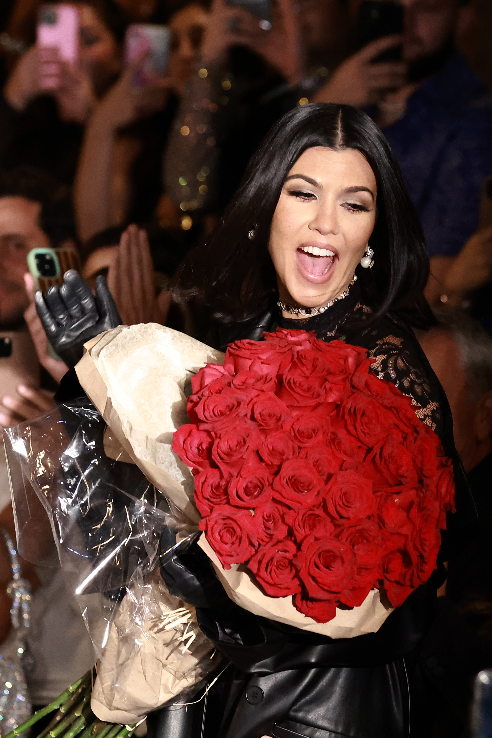 Close-up of Kourtney holding a bouquet of many red roses