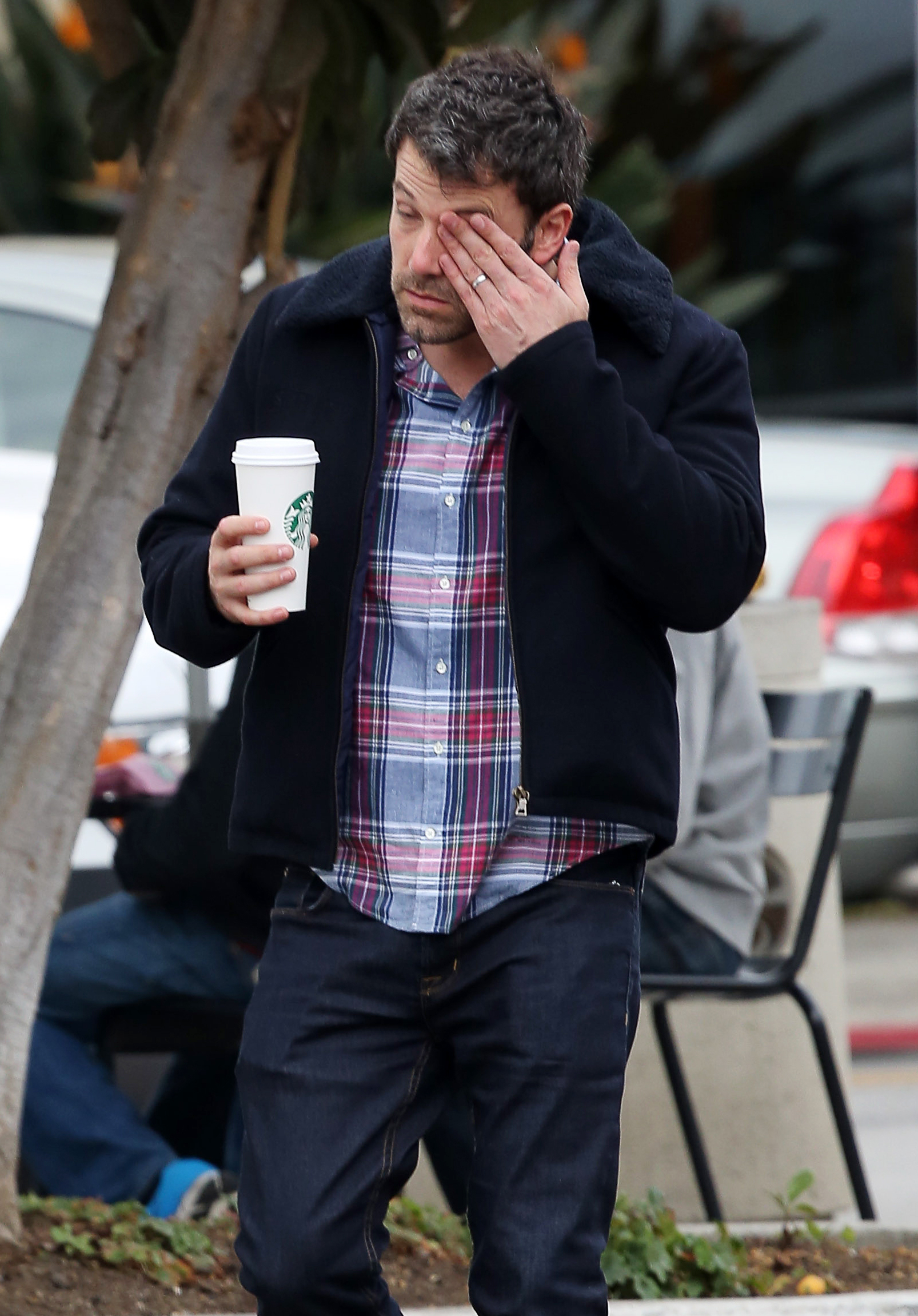 Closeup of Ben Affleck holding coffee and rubbing his eye