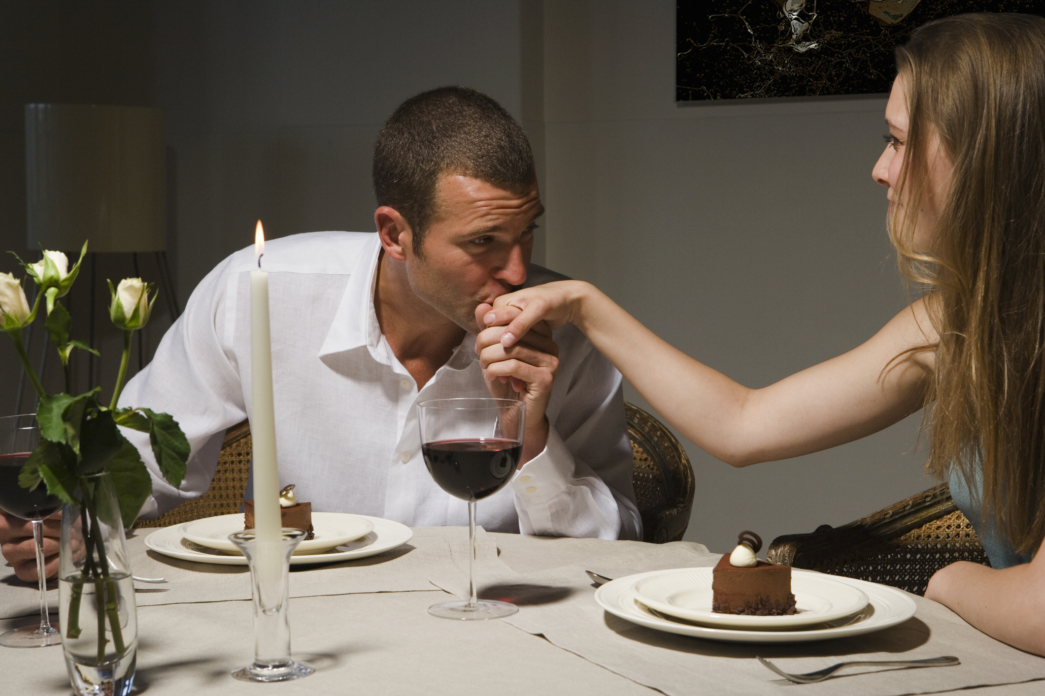 guy kissing his date&#x27;s hand at dinner