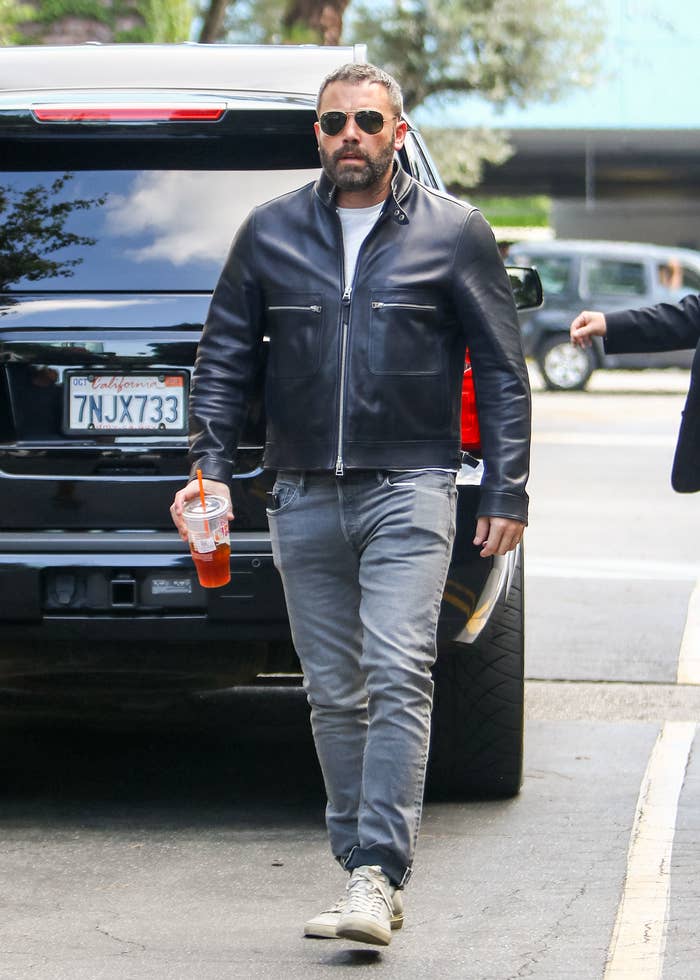 Closeup of Ben Affleck walking holding a Dunkin drink