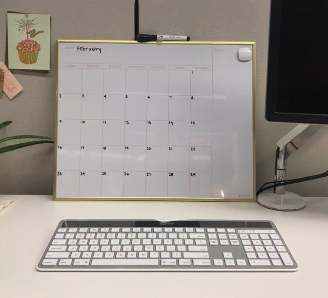 Wall calendar showing the month of February with dates, hung above a computer keyboard on a desk