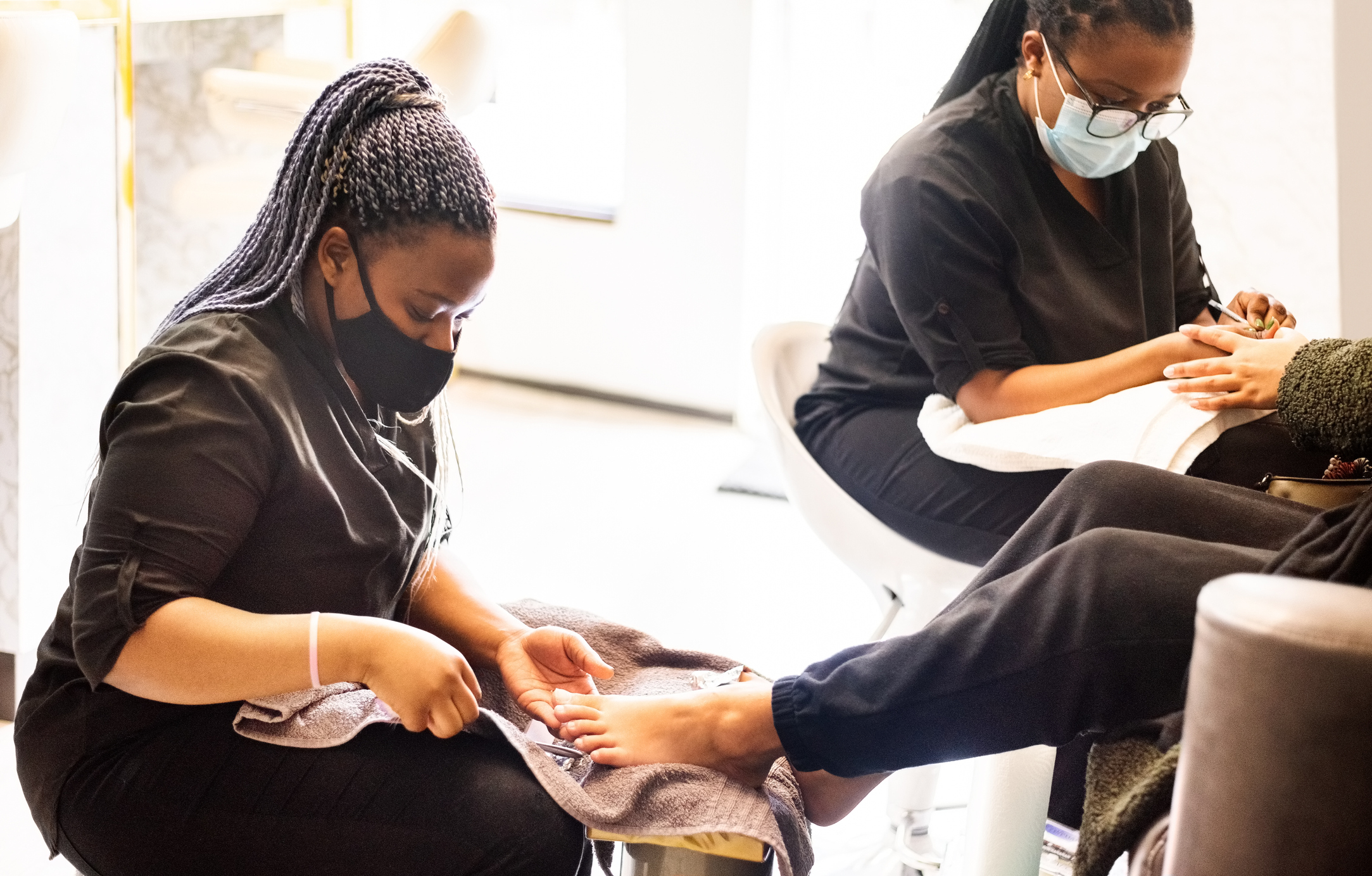 Nail techs working on someone's feet and hands