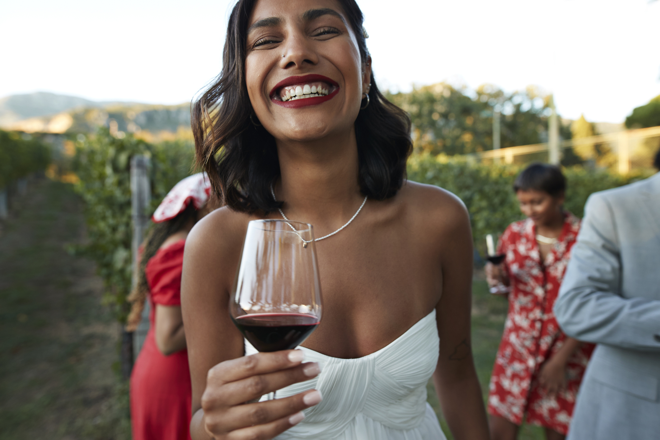 A bride smiling with a glass of wine in her hand