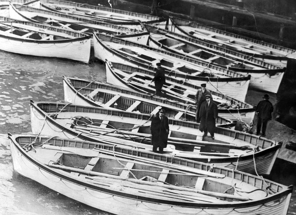 Small rowboats next to each other in the water with men standing in a few of them