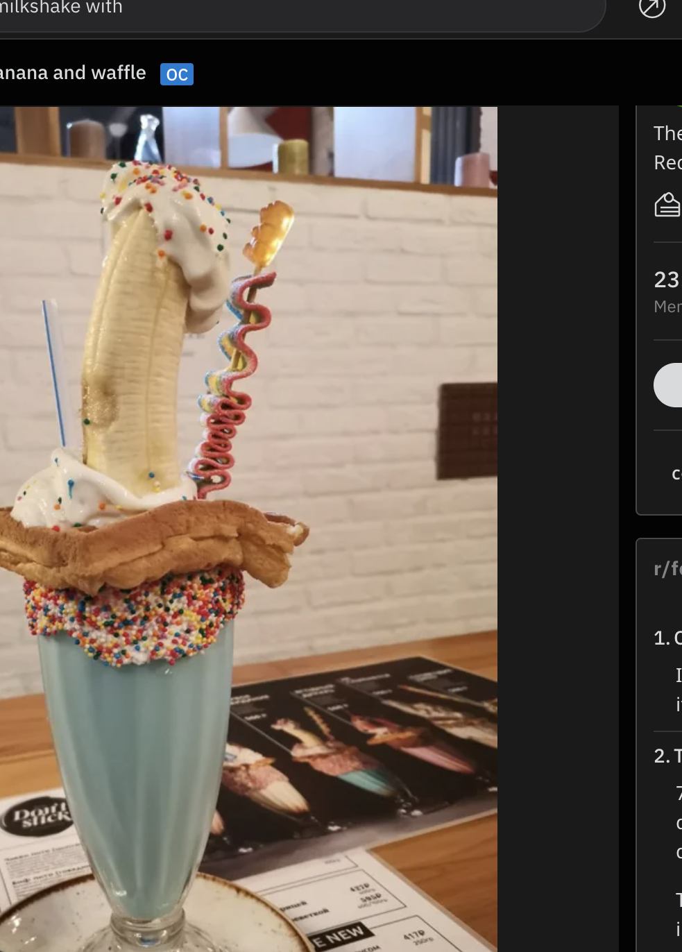 A milkshake is stacked with sprinkles, a waffle, a banana, sour candy, and whipped cream