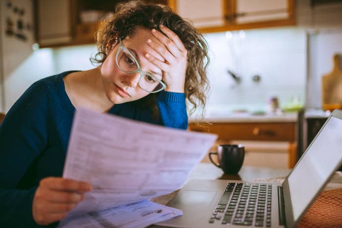 Woman reading through a bill in her home while looking stressed