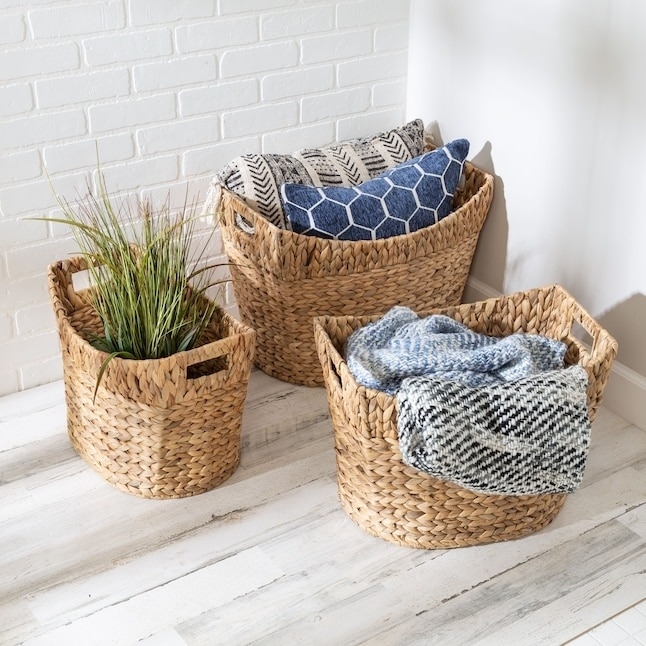 three wicker storage baskets with linens and a plant
