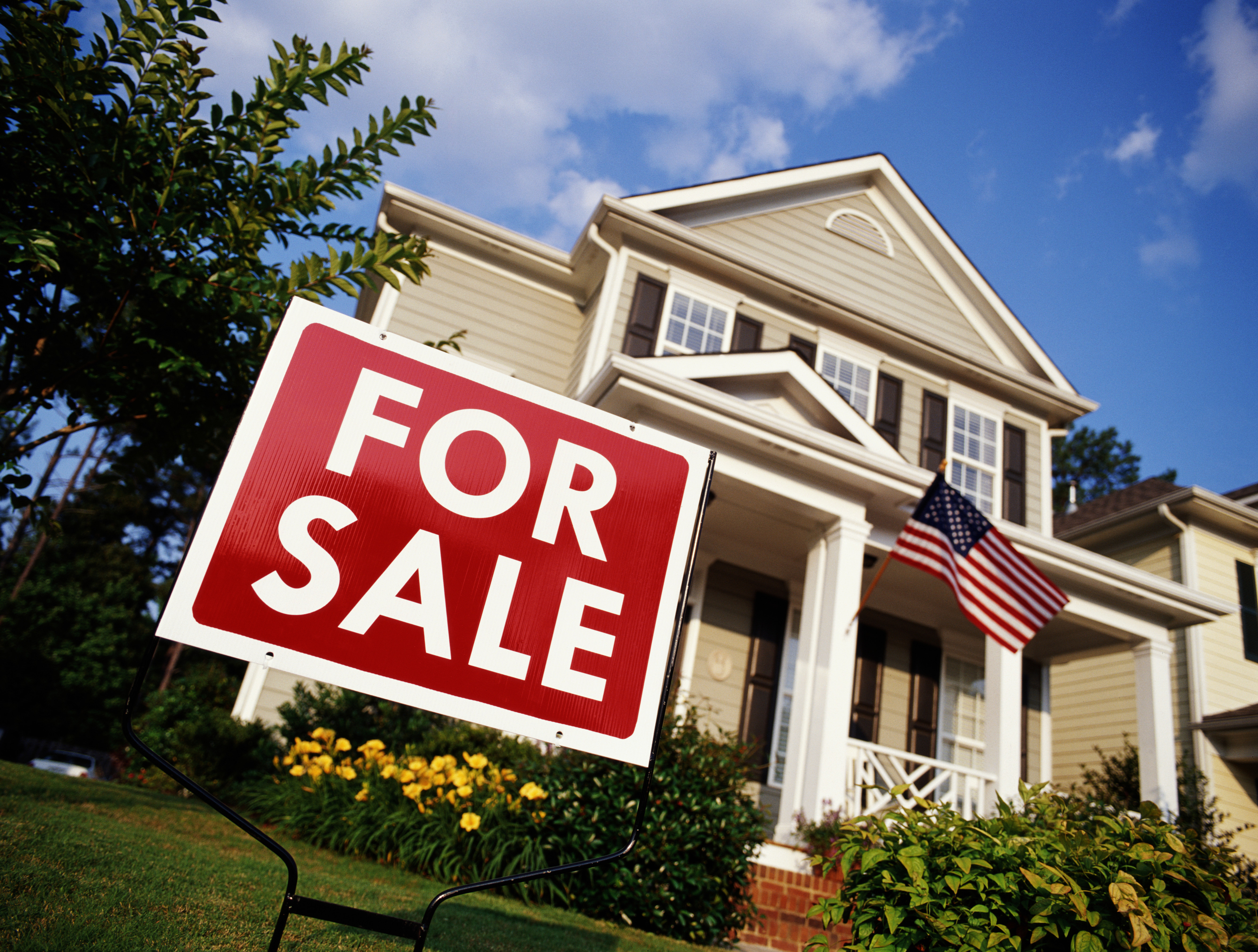 for sale sign in front of a large house