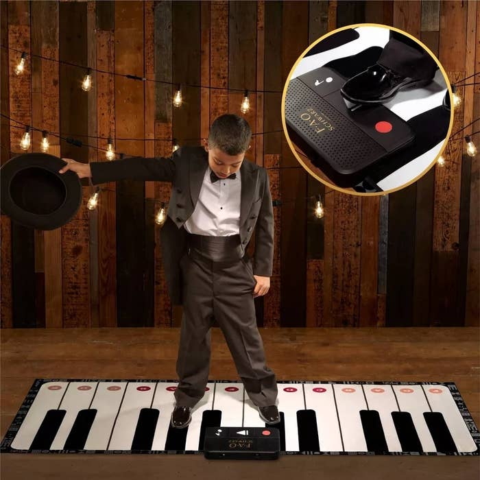 a kid standing on the piano keyes with a suit on