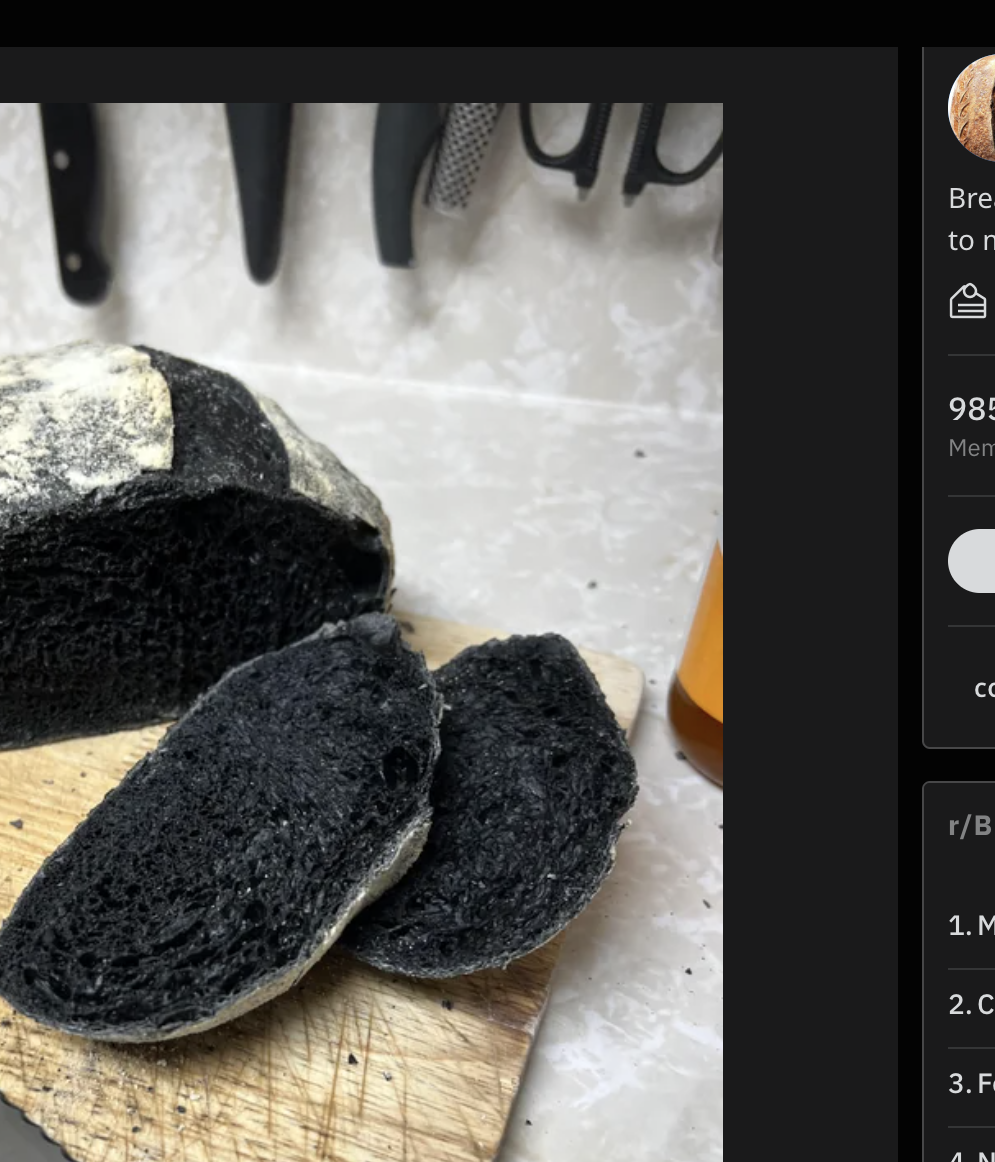 A loaf of charcoal bread is being cut