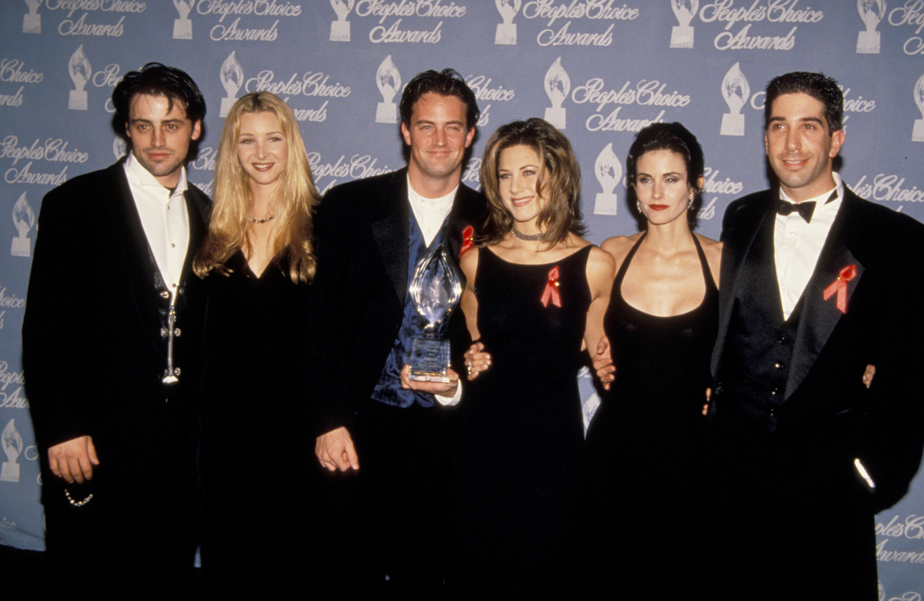 The cast of &quot;Friends&quot; on the red carpet holding an award