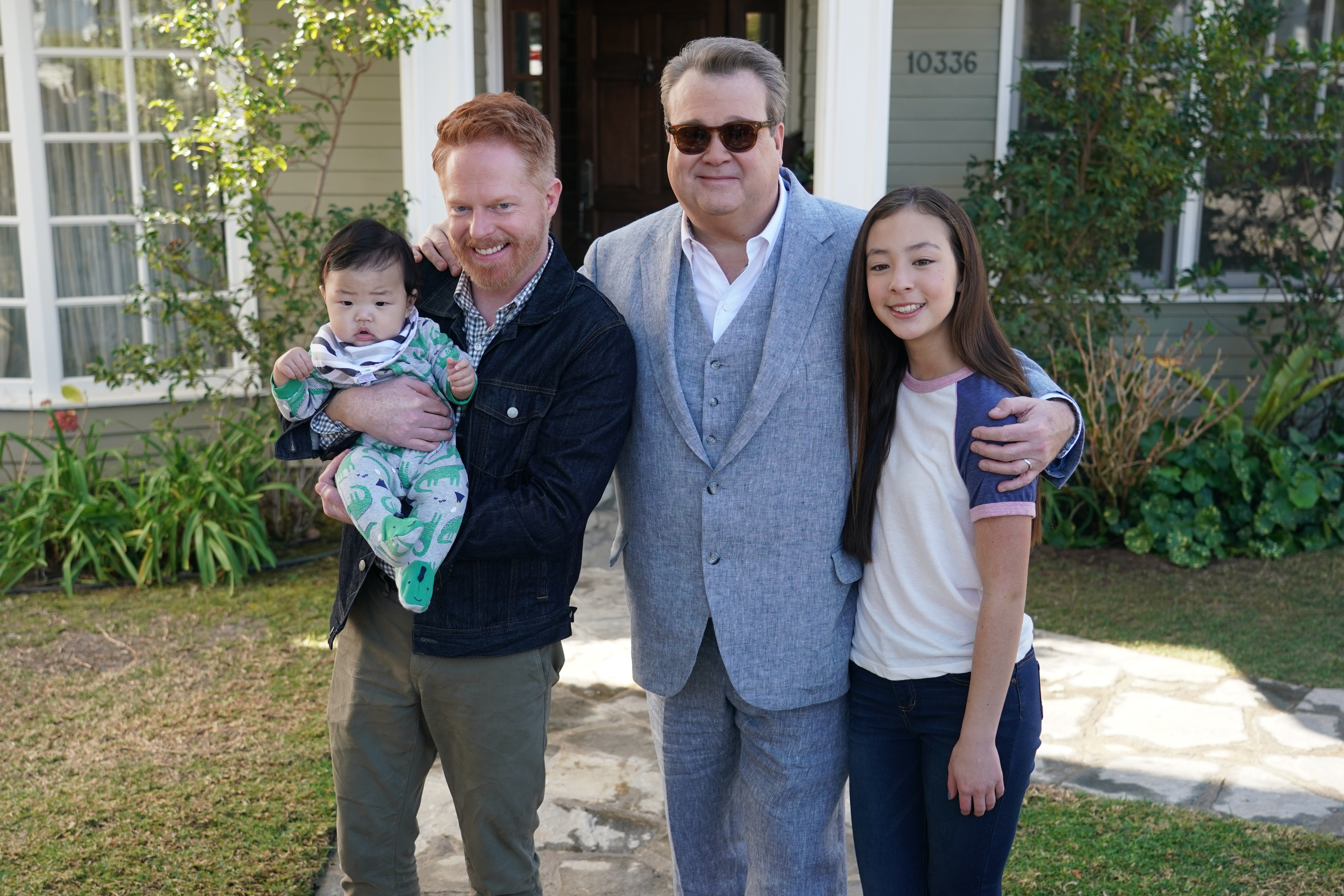 Mitch, Cam, Lily, and a baby standing in front of a house on the modern family series finale
