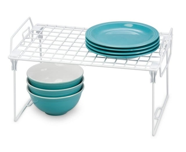 the wire shelf organizer with plates on it and bowls under it