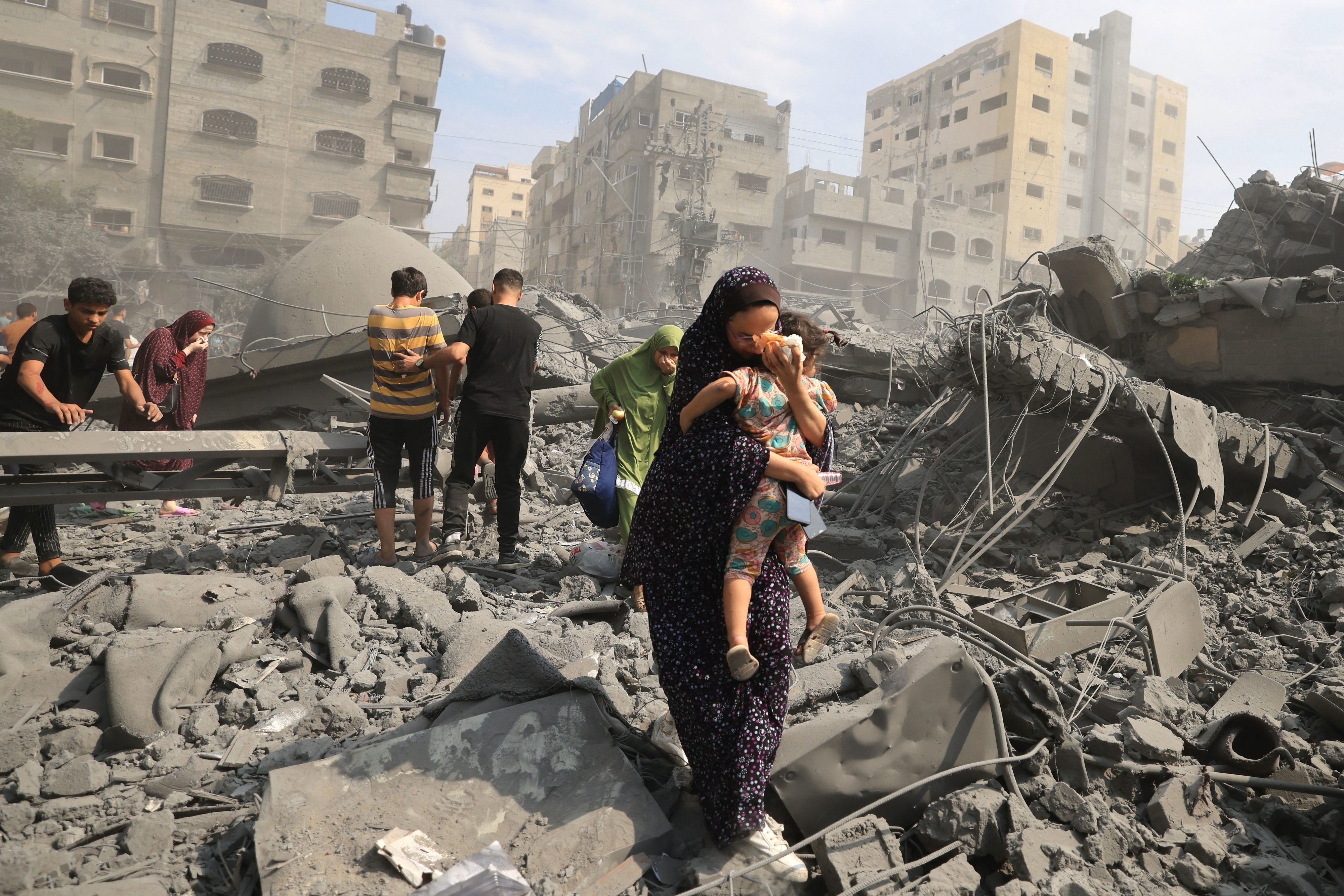 Palestinian civilians walking through the wreckage