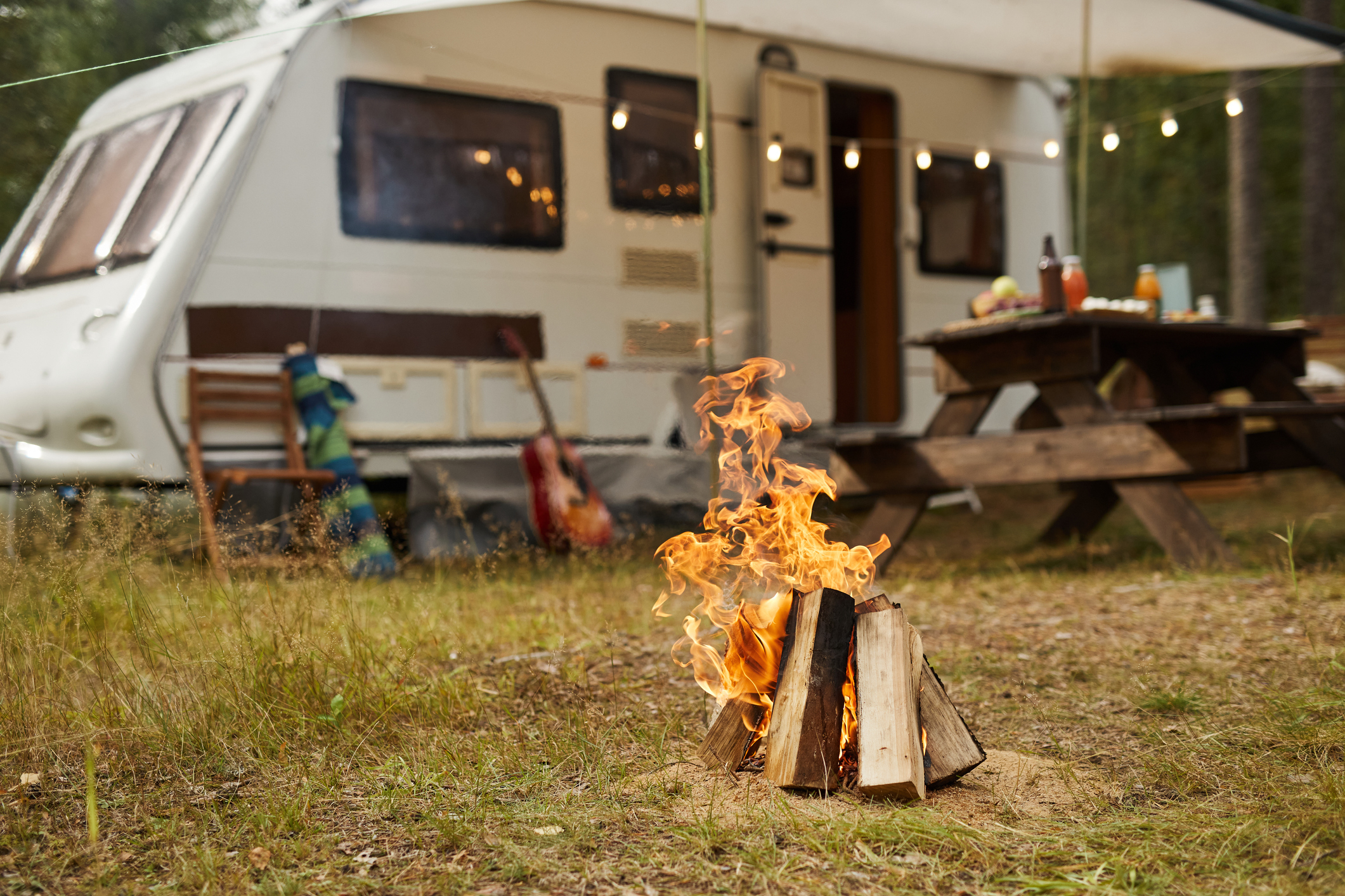 Background image of campfire in forest with trailer van in background