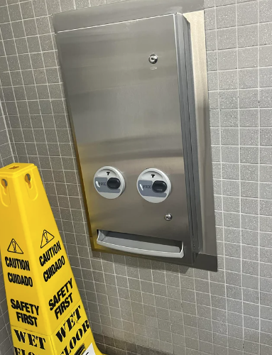 dispenser in a bathroom looks like it has a pair of eyes looking to the right