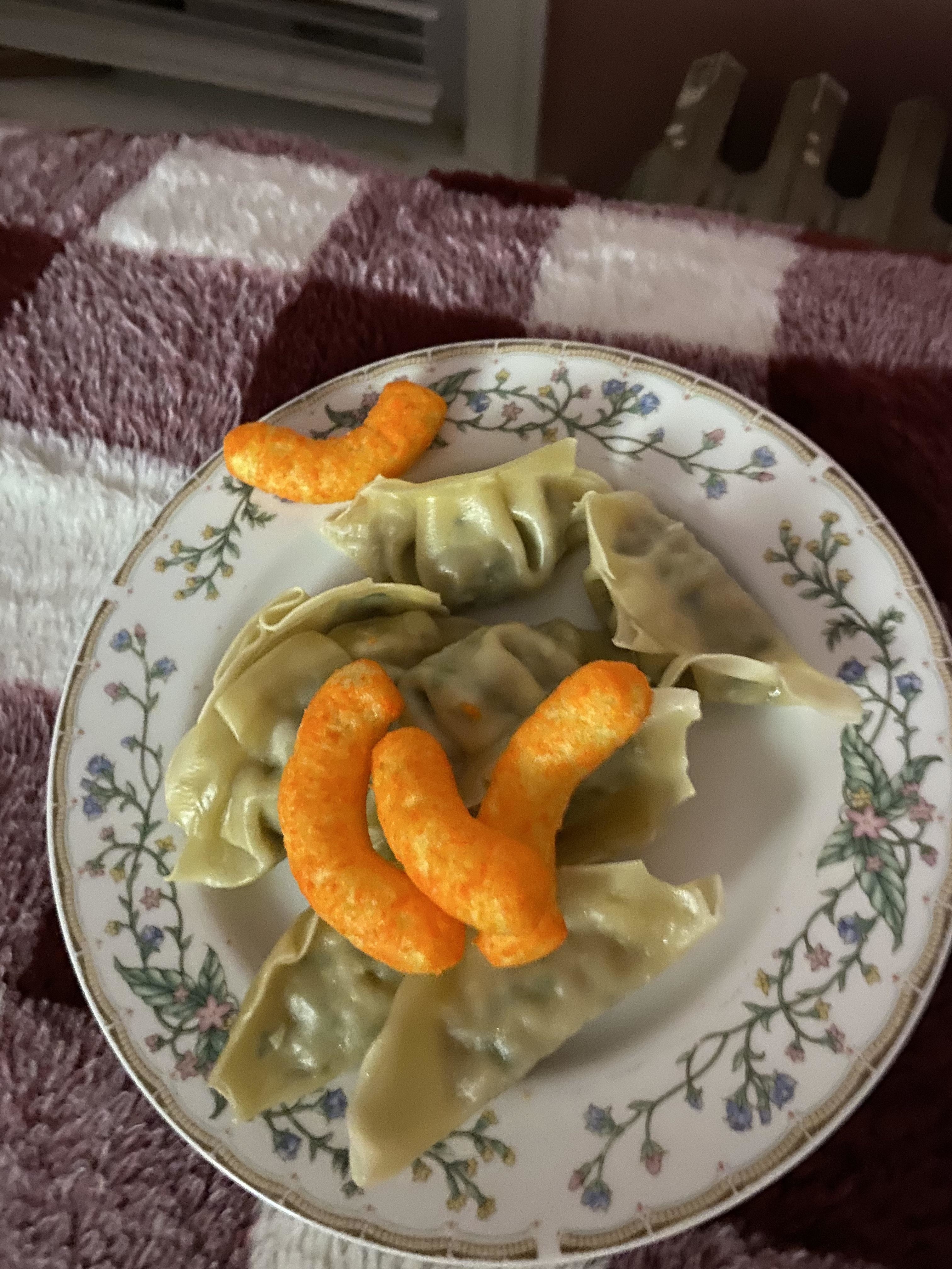 a plate with a handful of steamed dumplings and four cheetos on top