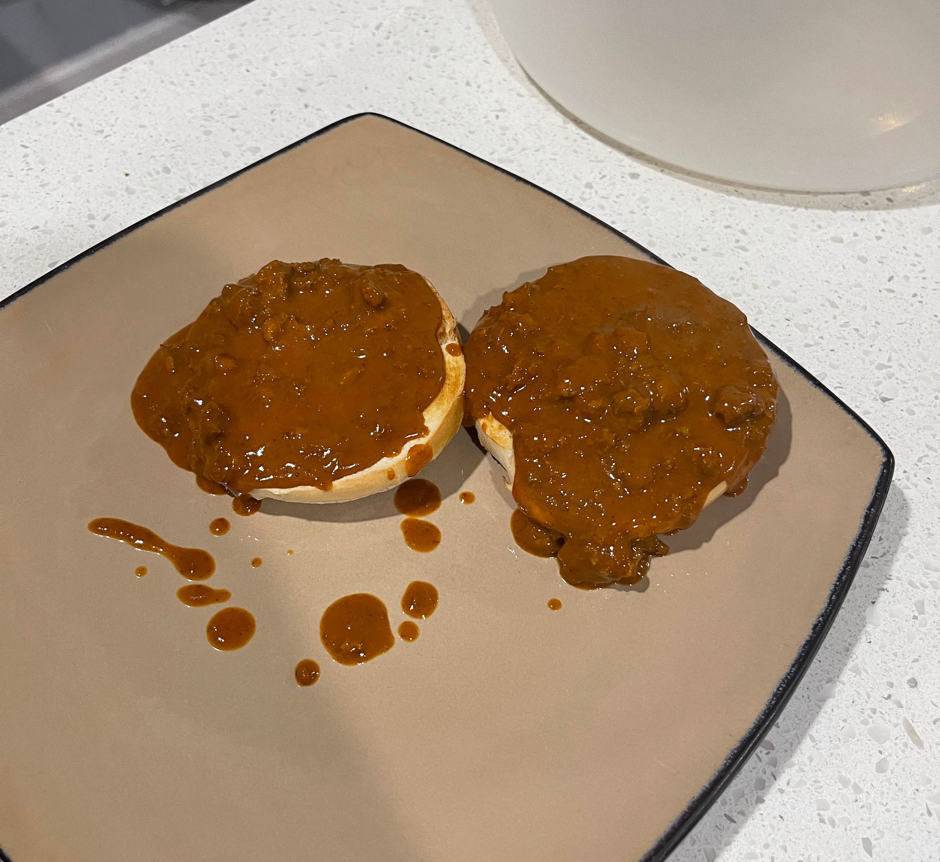 a toasted bagel cut in half with a ton of sloppy chili drowning it
