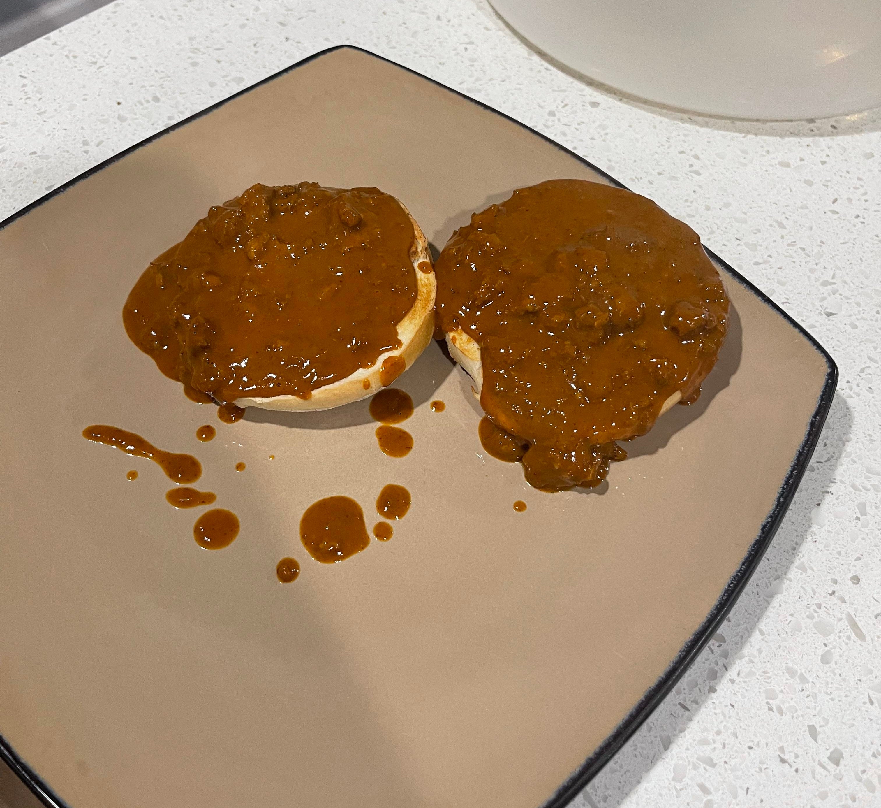 a toasted bagel cut in half with a ton of sloppy chili drowning it