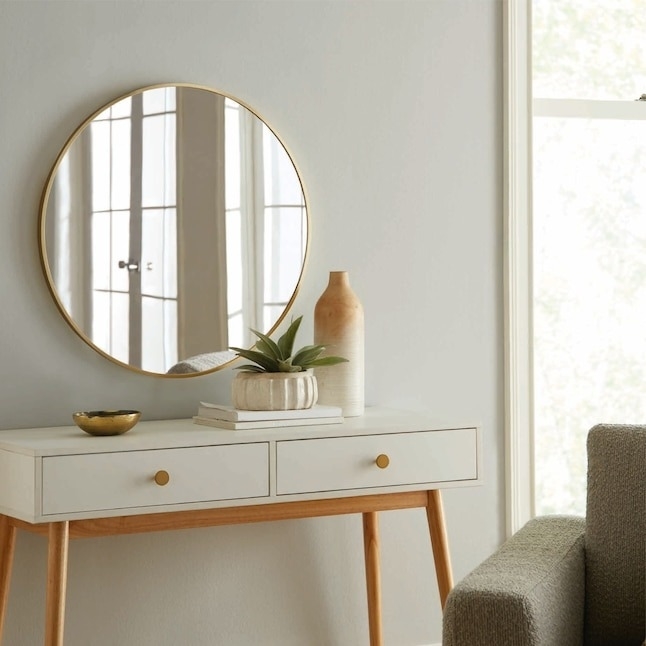 the round mirror with gold trim in an entryway