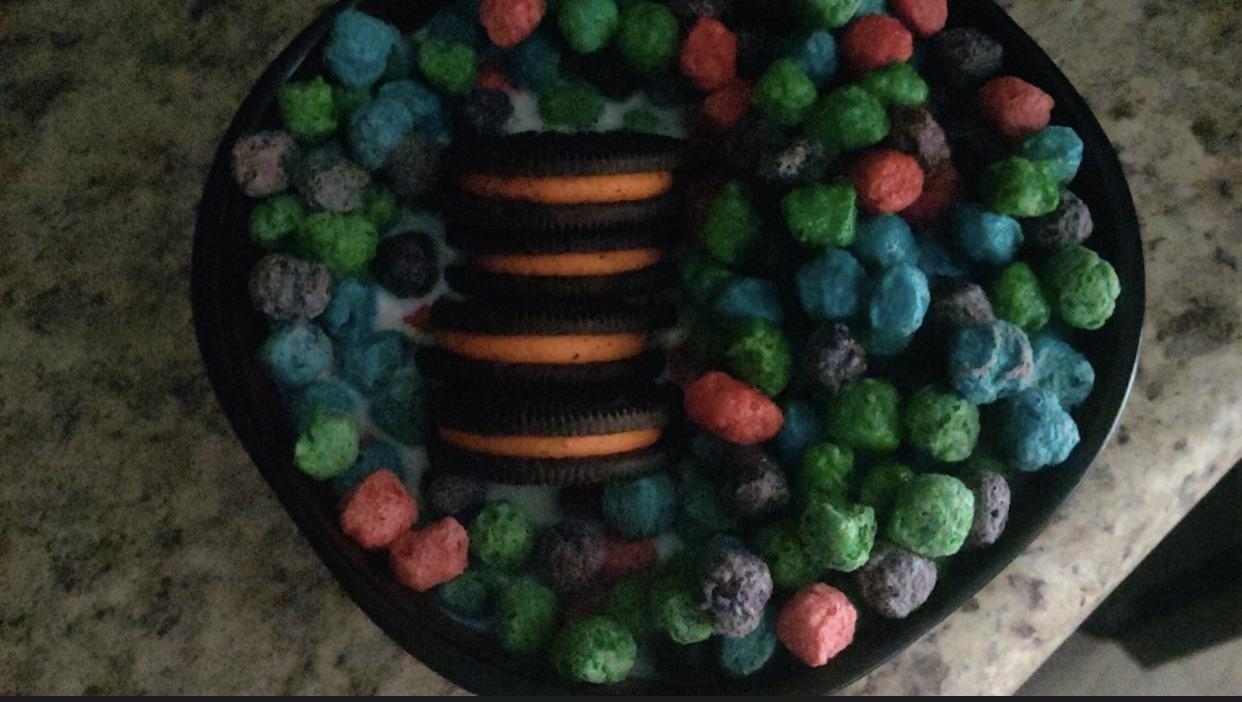 a bowl of sugary fruit cereal with four halloween oreos in it, too