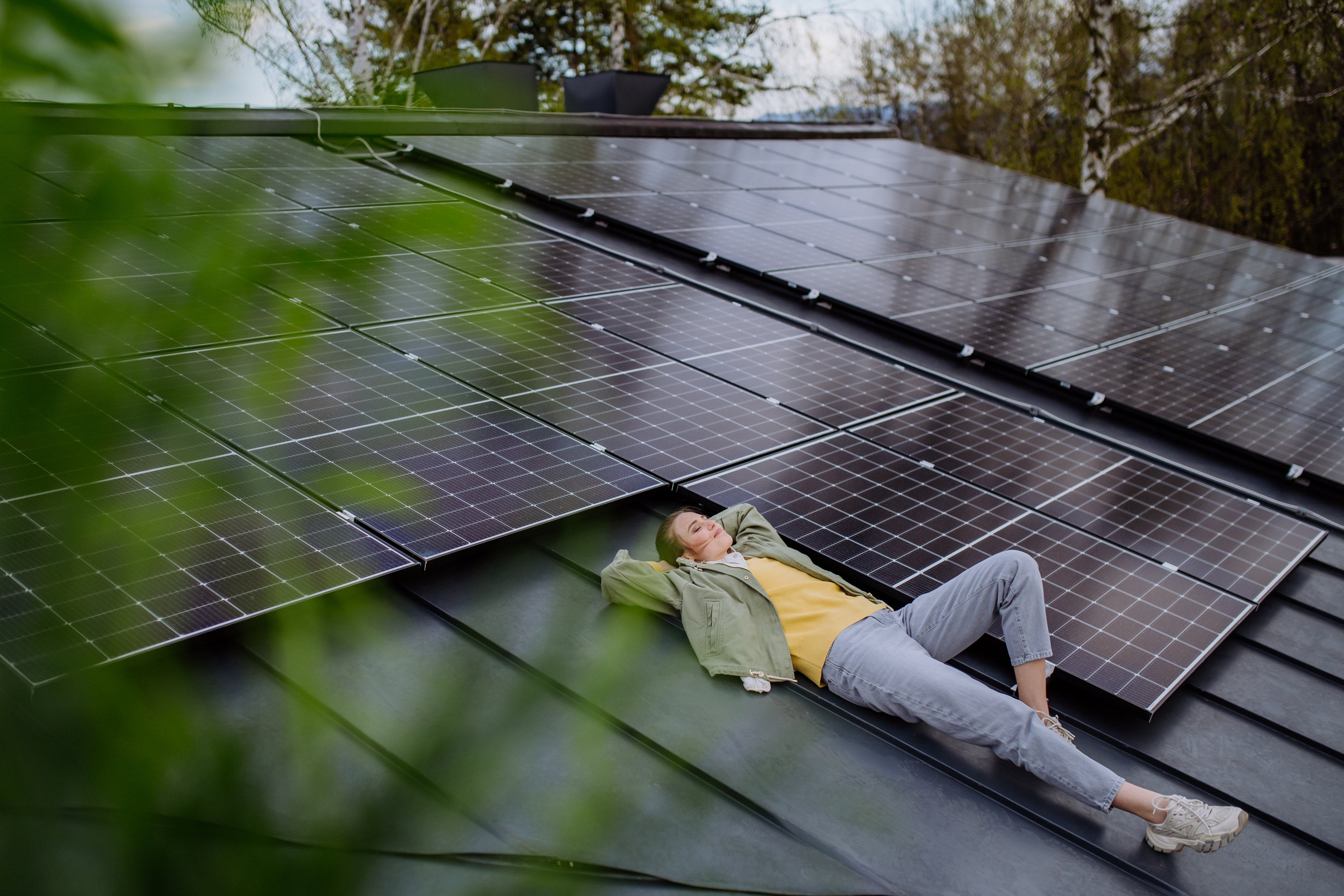 woman laying on her roof next to solar panels