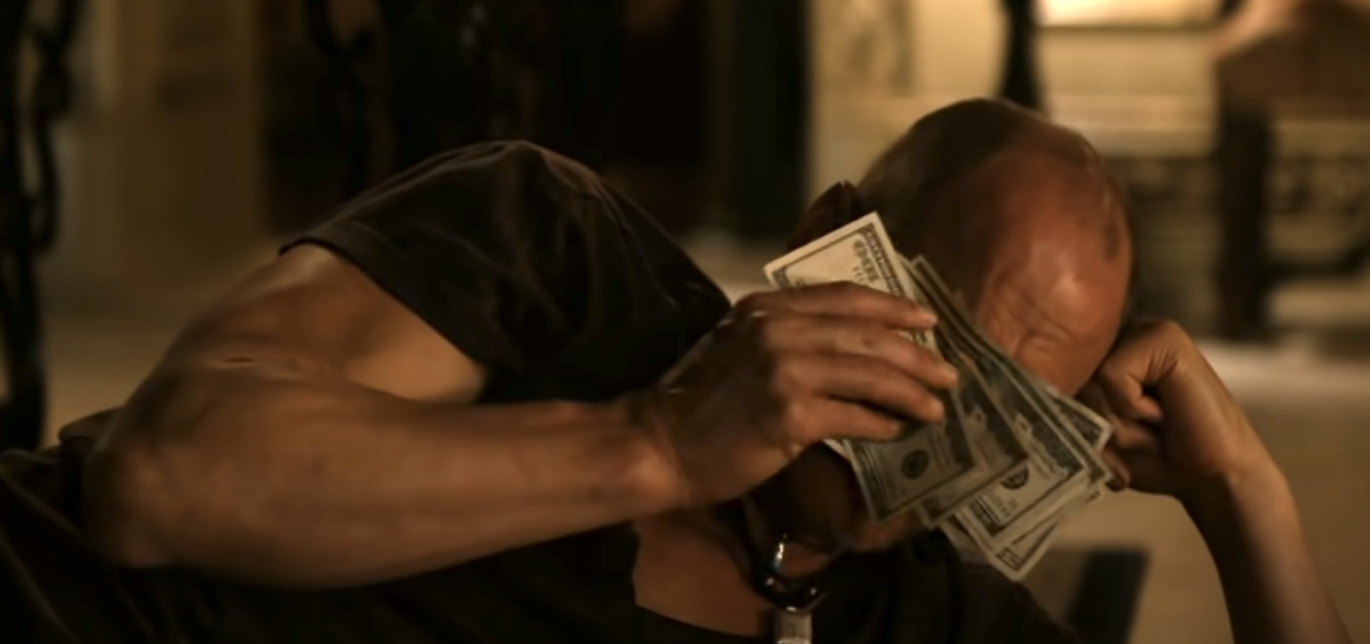 Woody Harrelson wiping his eyes with a wad of cash as Tallahassee in Zombieland