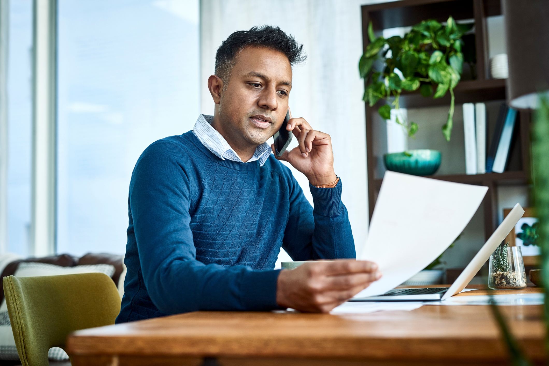 man at his desk on the phone and looking at a paper