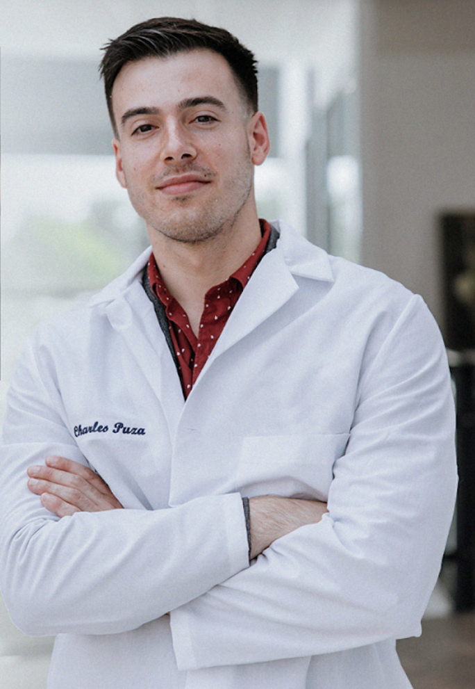 Dr. Charles wearing a doctors coat with his name Charles Puza embroidered on the pocket