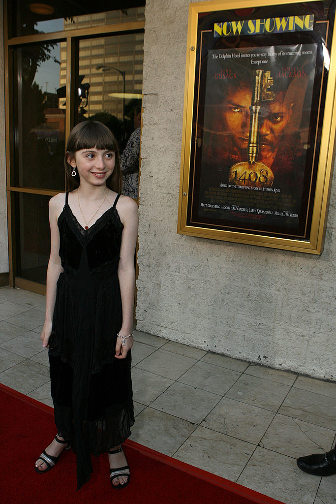 A young girl standing in front of a movie poster
