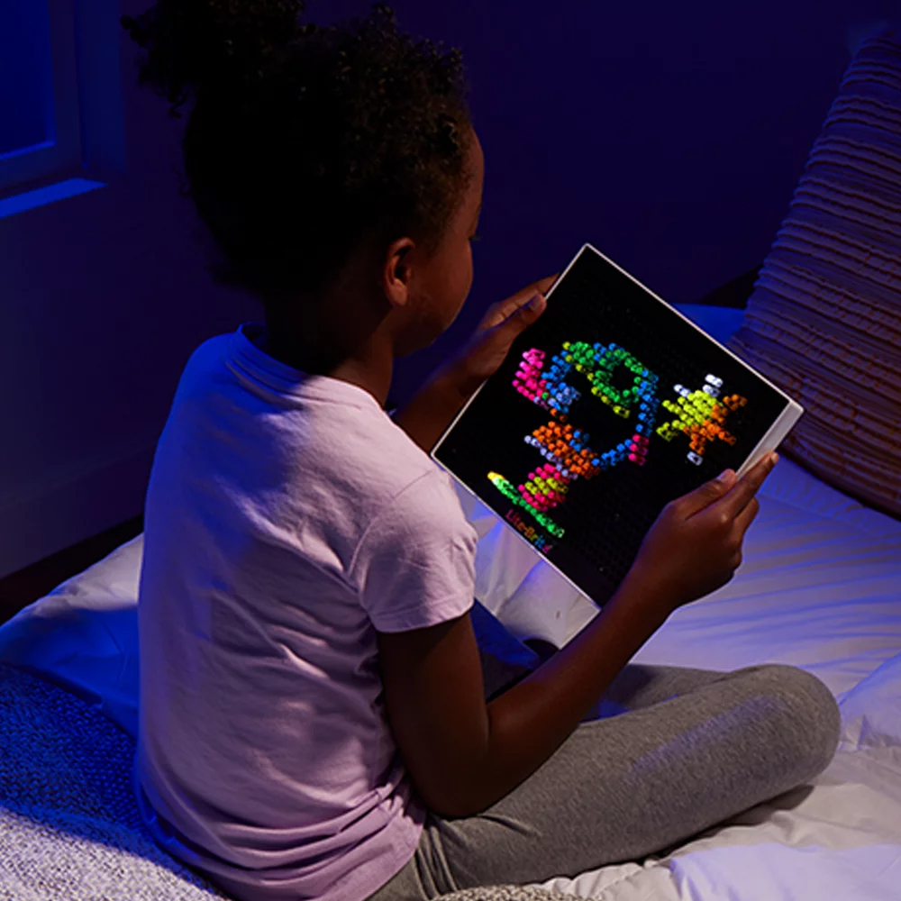 a child playing with the lite brite in bed