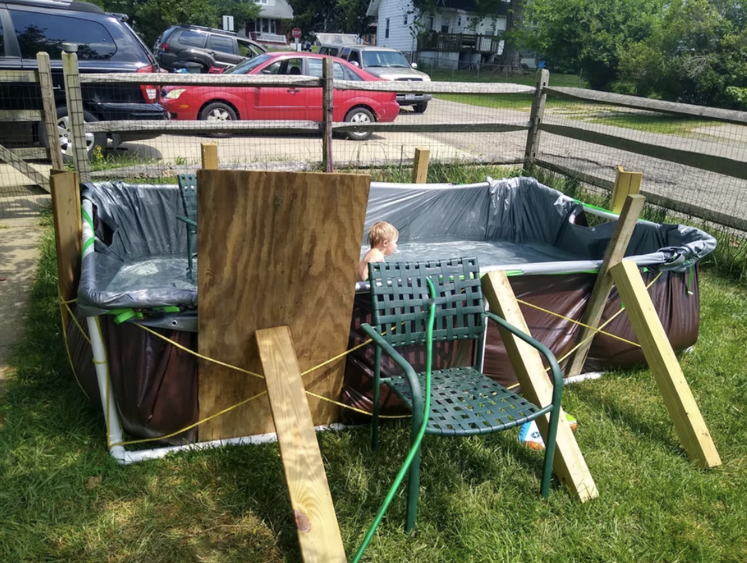 A DIY pool made of a tarp and held together with bungee cords, pipes, and wood