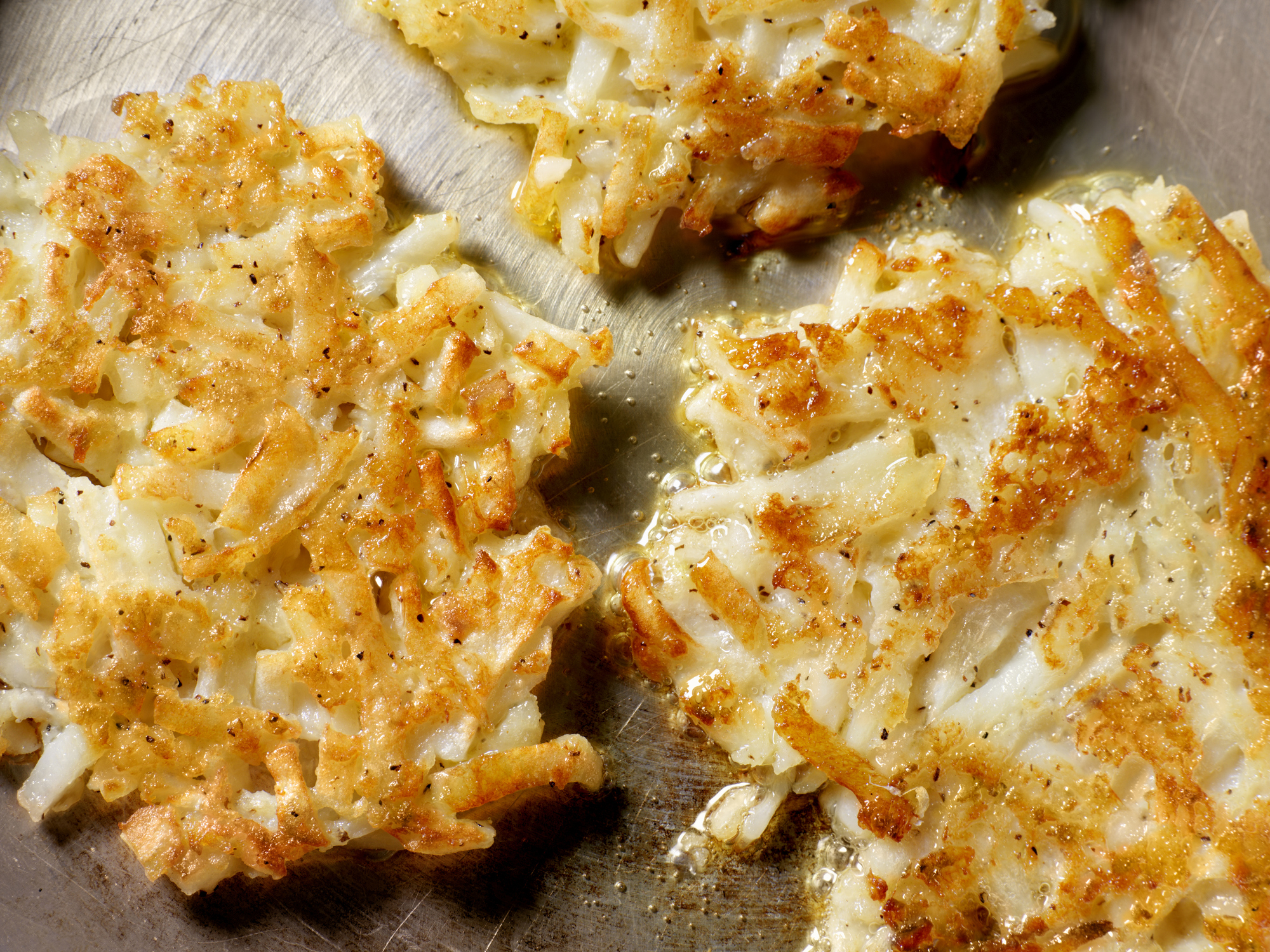 crispy hash browns sizzling in a pan with oil
