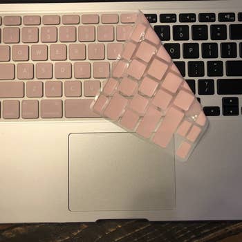 the keyboard cover in pink partially covering a laptop keyboard