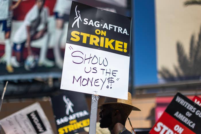 Close-up of a sign on the picket line: &quot;Show us the money!&quot; with a dollar sign