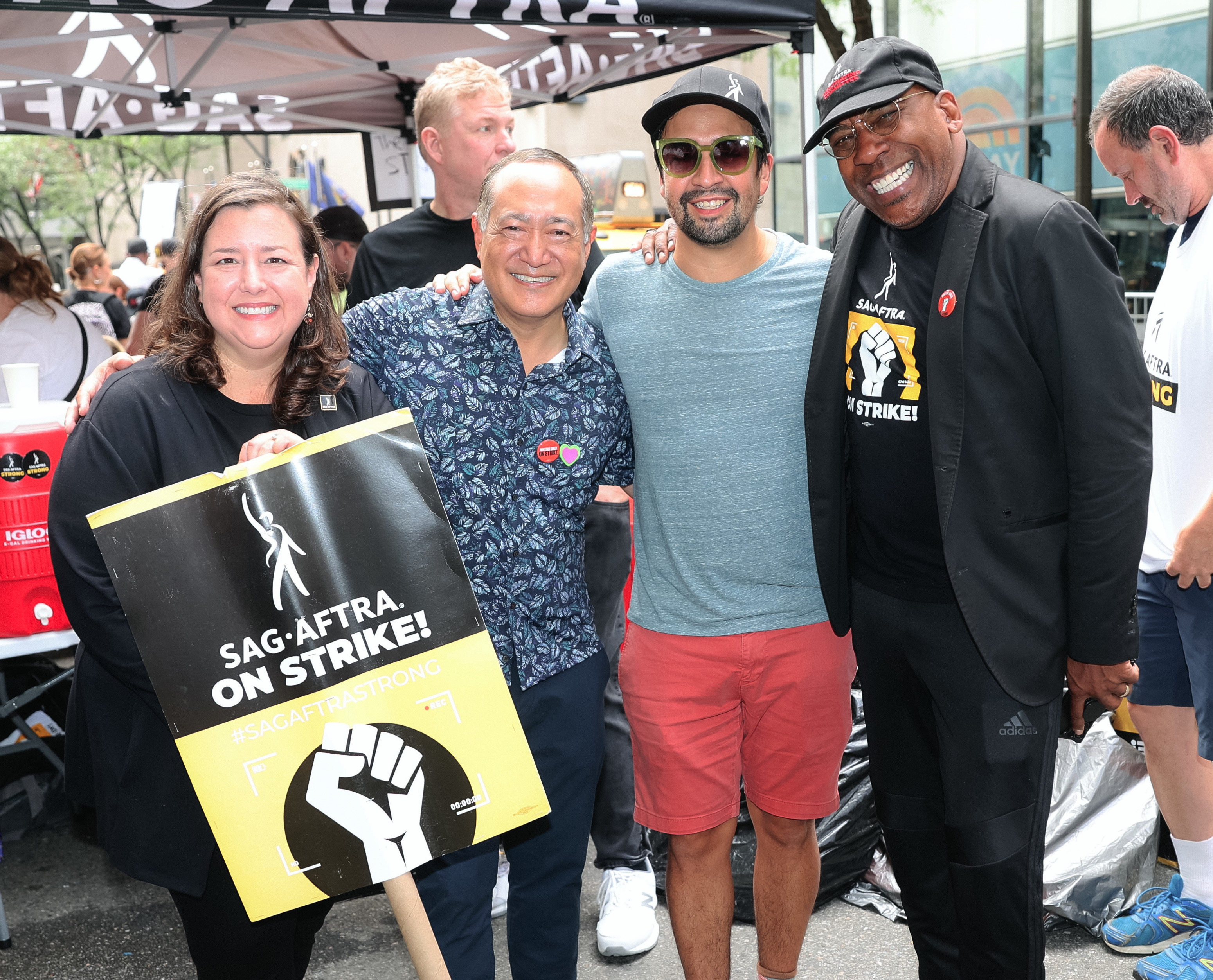 People, including Lin-Manuel Miranda, smiling on the picket line