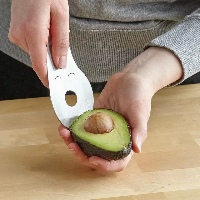 model using the avocado multi-tool to scoop avocado