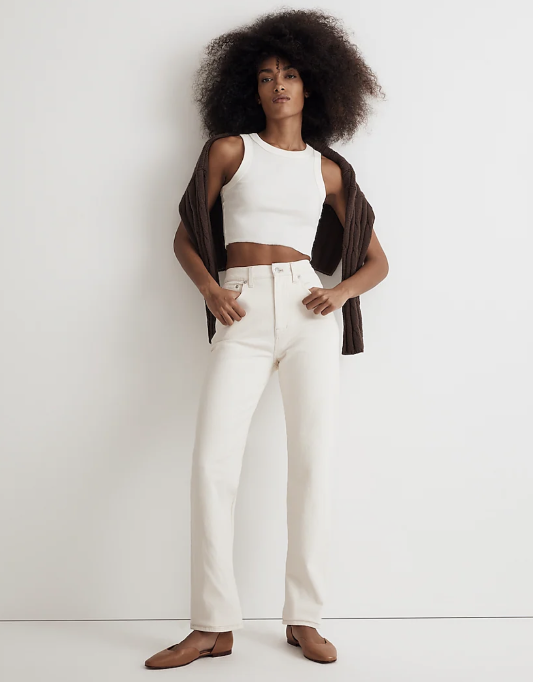 Model wearing white jeans, white sweater, and tan shoes