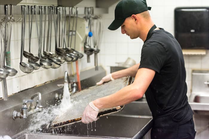 a man washing the dishes in the back of the kitchen