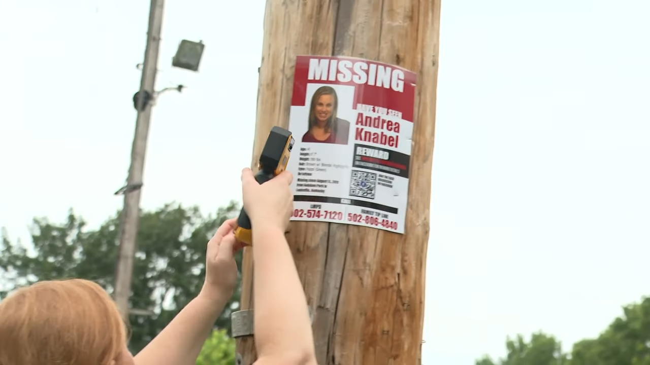 someone posting a missing person poster on a pole