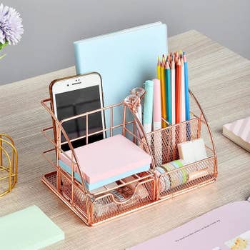 the desk organizer holding colored pencils, a phone, and other office supplies