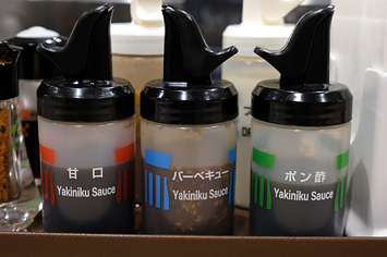 松屋にある調味料ボトル。「甘口」「バーベーキュー」「ポン酢」の全ての英文表記がも「Yakiniku Sauce」となっている（都内で撮影）