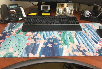 a colorful blue and green cactus themed desk mat on reviewer's work desk
